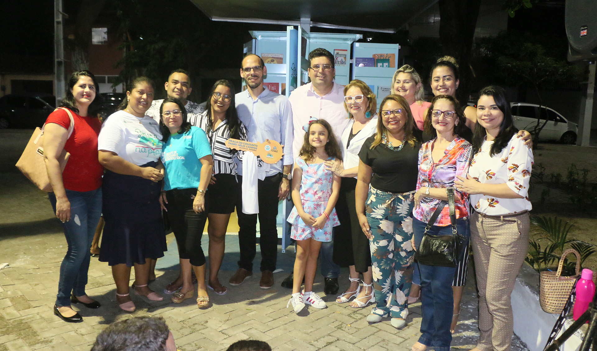 grupo de pessoas na frente de um quiosque de leitura posando para a foto